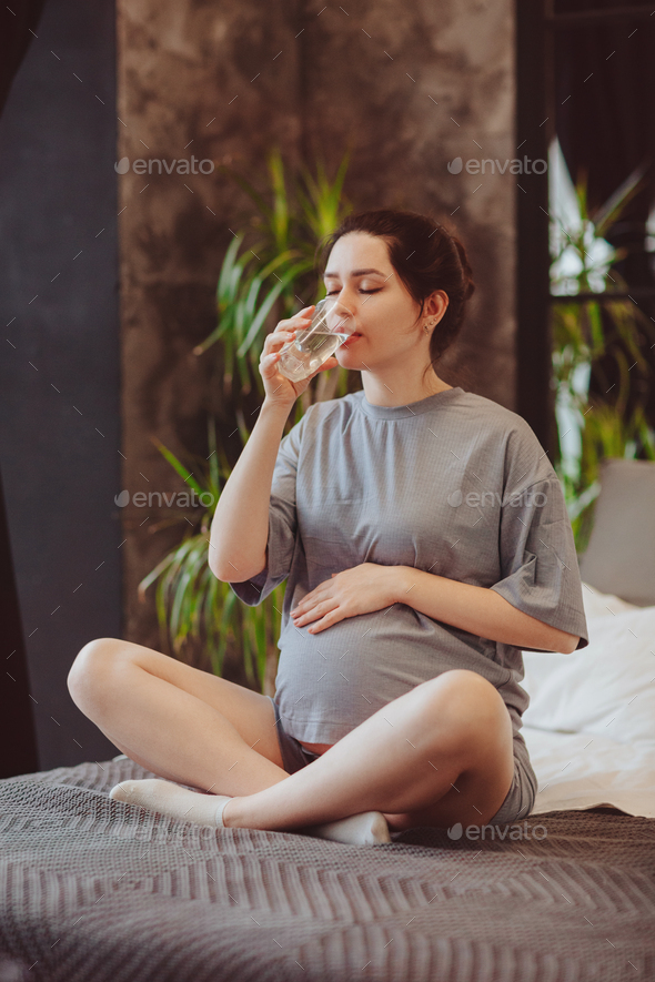 Hydration during pregnancy. Young pregnanat woman drinking clean mineral water in morning