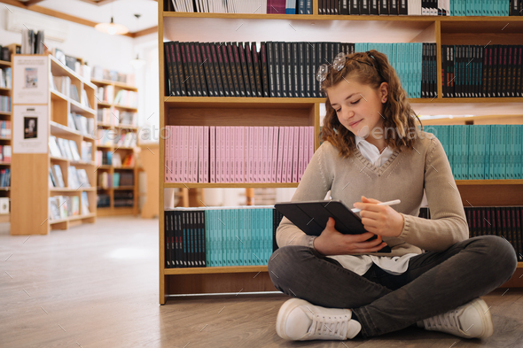 Beautiful Girl Is Studying While Sitting On The Floor Among Books In ...