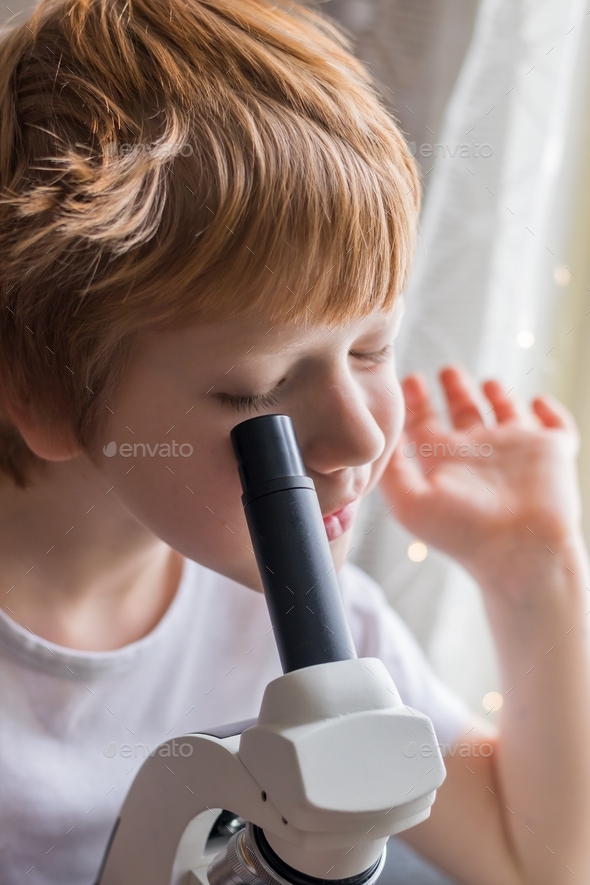 a child studying glasses with laboratory materials under a microscope with great interest