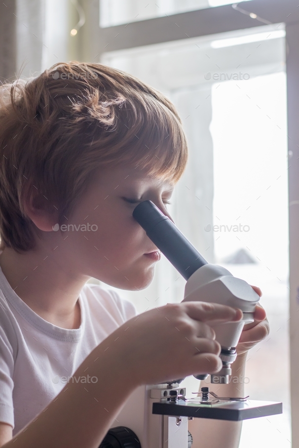 a child studying glasses with laboratory materials under a microscope