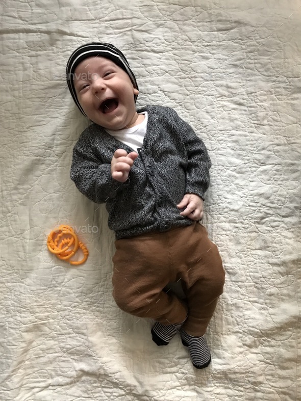 Cutest baby boy laughs as he lays on a cozy blanket