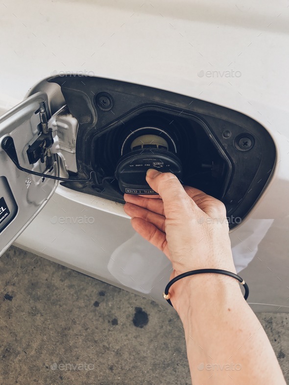 Hand removing a gas cap at a gas station Stock Photo by debbalba
