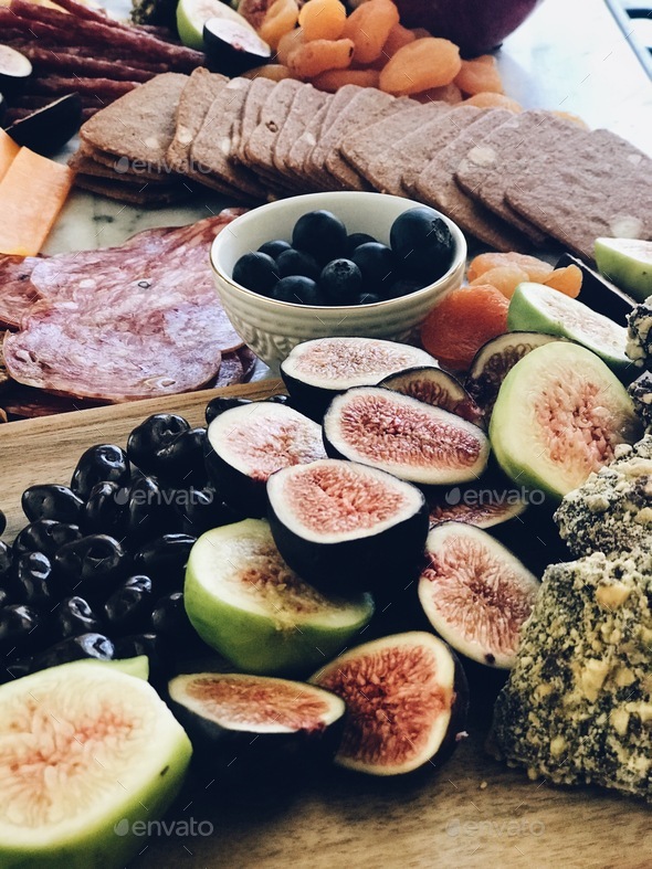 Fruits, nuts, olives and meats grace a charcuterie board Stock Photo by
