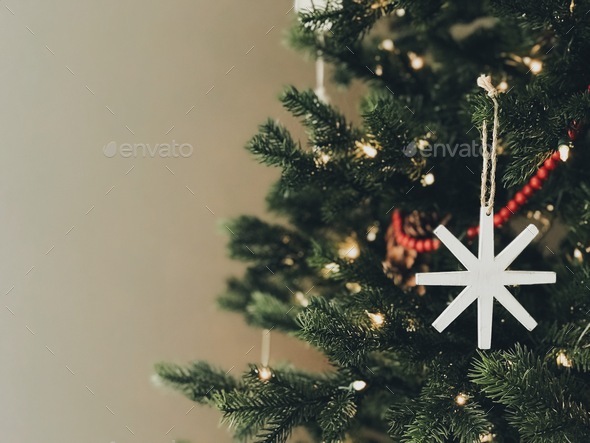 A green pine tree decorated with a white star, white lights, red beads for honoring  Jesus’ birth - Stock Photo - Images