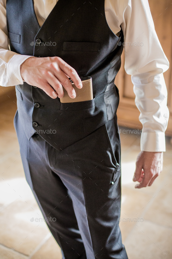 Groomsman pulling a small leather flask from his vest pocket