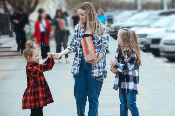Family on a walk in the city, mom feeds her daughters with ready meals