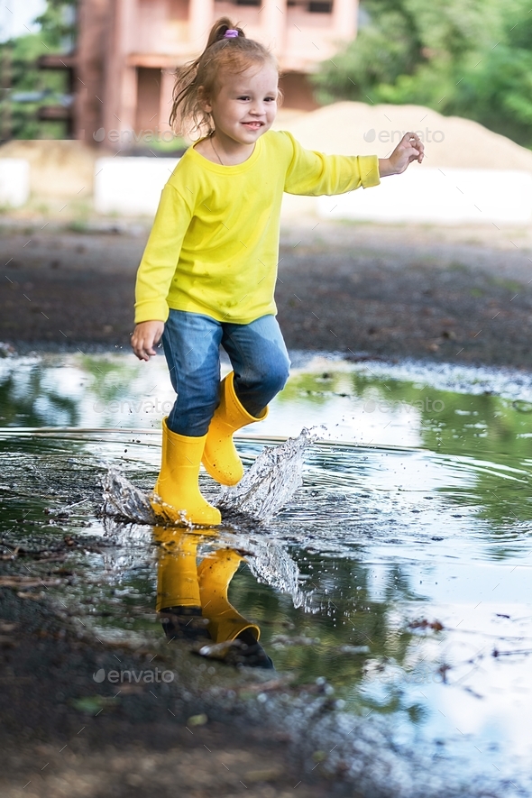 little girl joyfully runs through the puddles