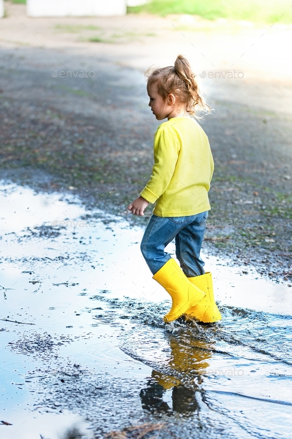little girl joyfully runs through the puddles