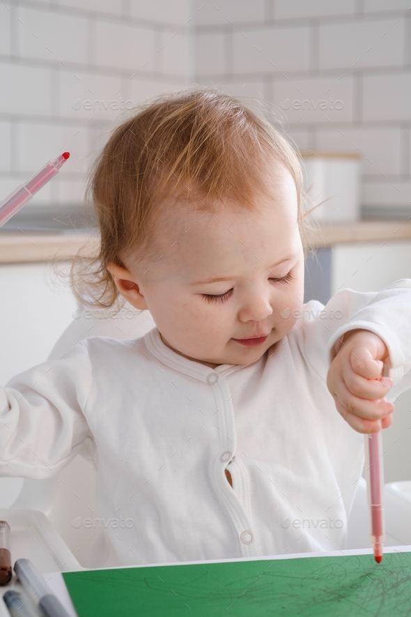 Close up of a baby toddler drawing a picture by left hand using colored  markers. Left handed child. Stock Photo by buregina