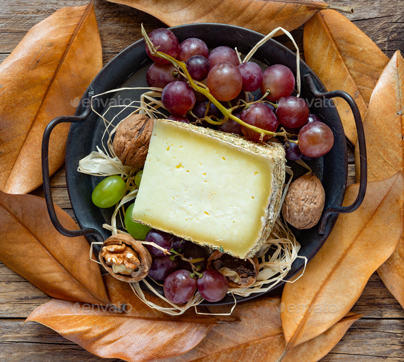 pecorino cheese with mountain hay, in autumnal background with black grapes - Stock Photo - Images