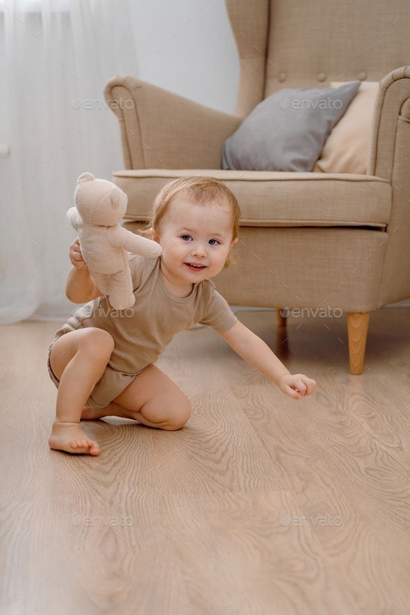 A cute smiling baby crawling forward holding a toy bear. Crawling abnormally.  - Stock Photo - Images