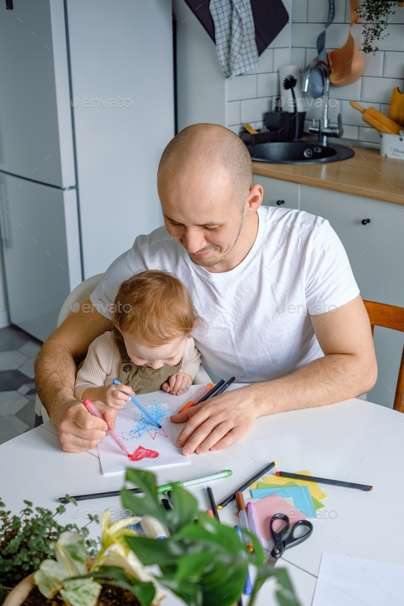 A cute baby toddler painting with father making a greeting card for ...