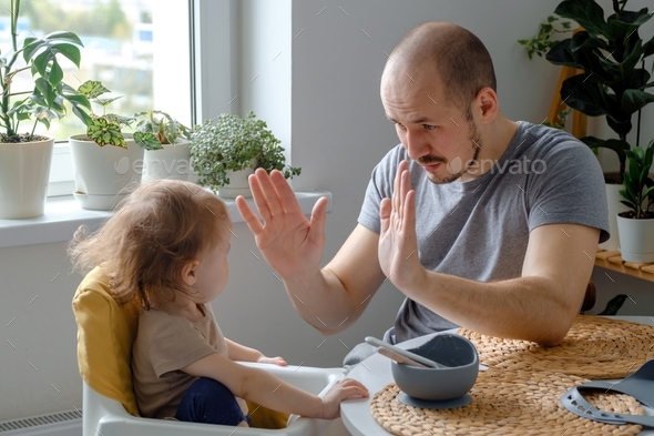 A father playing with baby toddler patty cake game. A dad teaching his child hands clapping game.