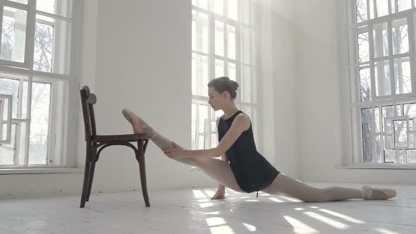 Ballerina doing te splits on the chair.