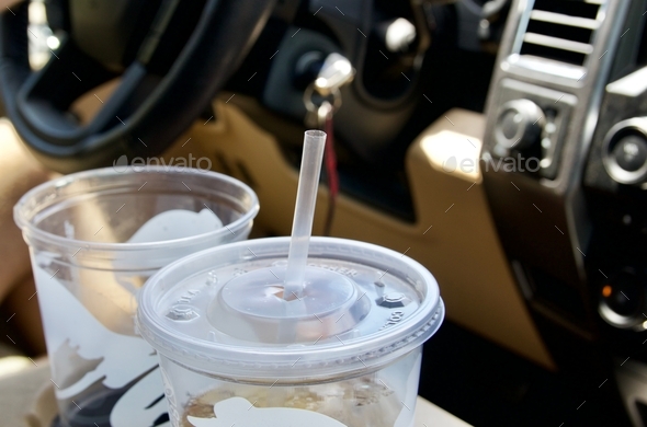 Large empty soda cups in cars cup holder on road trip
