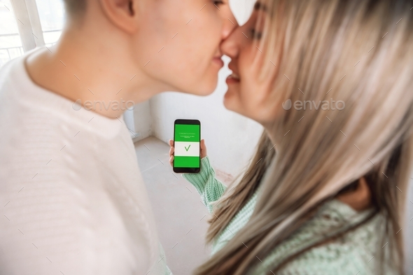 Mortgage approved online on a phone. Mortgage in internet. Man and woman kissing