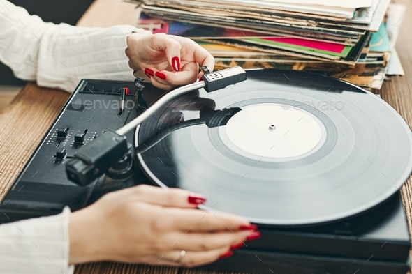 Woman playing music from vinyl record. Analog record. Retro and vintage style. Analog sound. Listen
