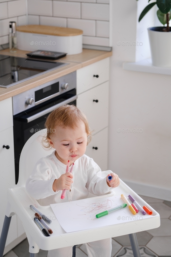 A cute little kid learning to draw (paint) using colorful markers. Developing new skills.  - Stock Photo - Images