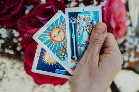 Fortune teller holding oracle cards in hand on flowers background. Tarot reader. Future prediction
