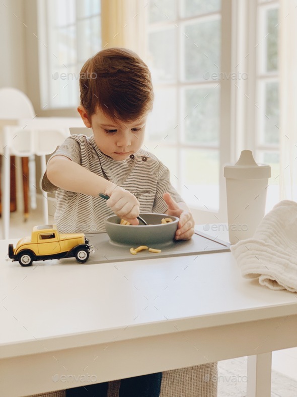 Young boy eating noodles at the table with his toy car. #debb_a/childhood, #debb_a/family - Stock Photo - Images