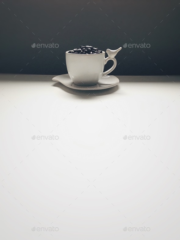 Coffee cup filled with coffee beans over a white background  - Stock Photo - Images