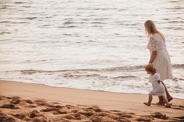Mother and daughter walking on a sandy beach #debb_a/motherhood, #debb_a/childhood - Stock Photo - Images
