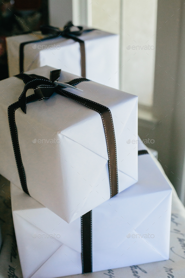 Wrapped packages in white with black ribbons are stacked - Stock Photo - Images