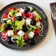 Greek salad on a round dish, cutlery and salt nearby. - PhotoDune Item for Sale