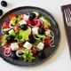 Greek salad on a round dish, cutlery and salt nearby. Light background. - PhotoDune Item for Sale