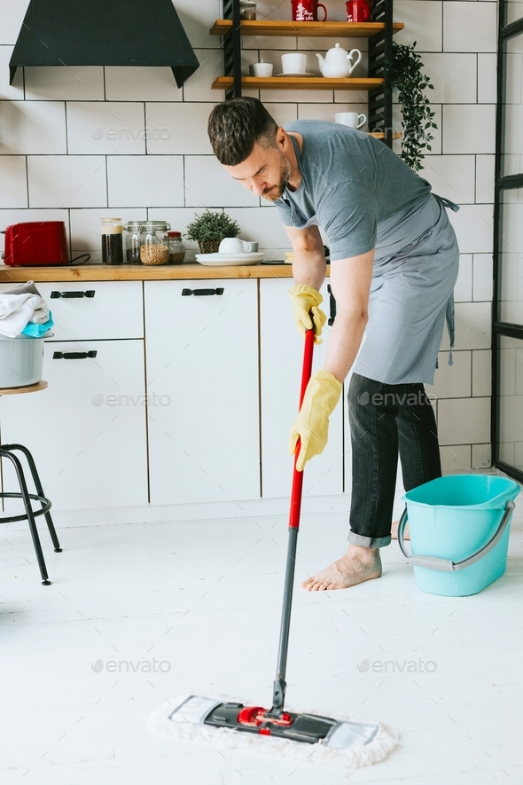 young man do household chores, men housework, household help in stylish kitchen in modern apartment,
