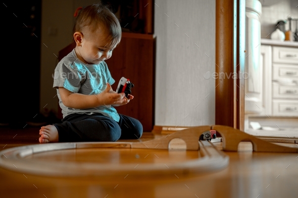 A small child is building a railway from wooden blocks. The boy is playing as a constructor - Stock Photo - Images