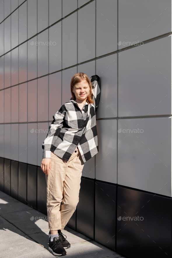A young girl on a white-gray wall background on a sunny day. - Stock Photo - Images
