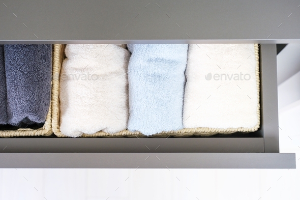 Folded towels in a wicker box in dresser close-up, space organization concept.