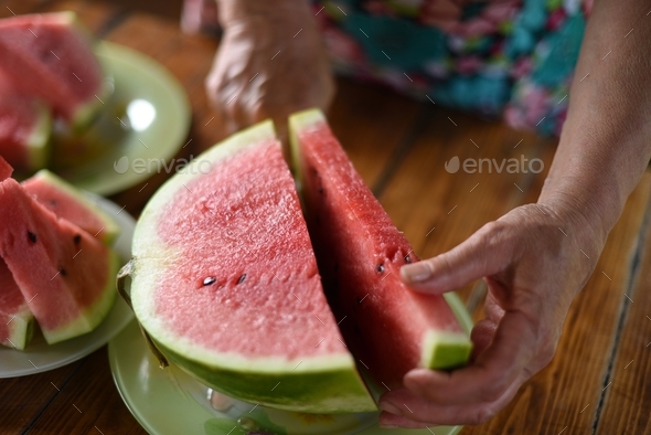 Fresh juicy watermelon on a sunny summer day hands of a woman cutting a watermelon - Stock Photo - Images