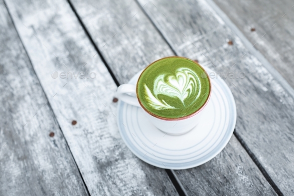 Cup of fresh green matcha latte beverage with latte art on foam. Background of wooden table - Stock Photo - Images