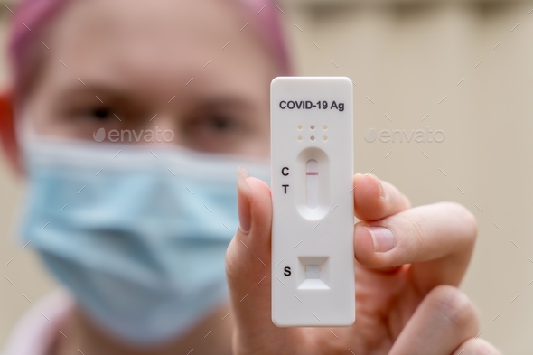 Teenage girl in face mask with negative Covid-19 Rapid Antigen test result. rapid diagnostic test