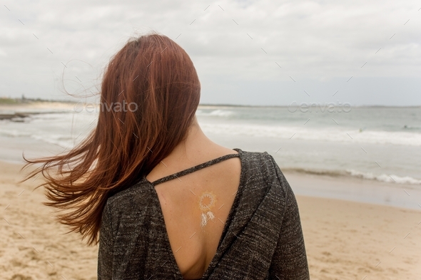 A girl with temporary tattoo on her back at the beach
