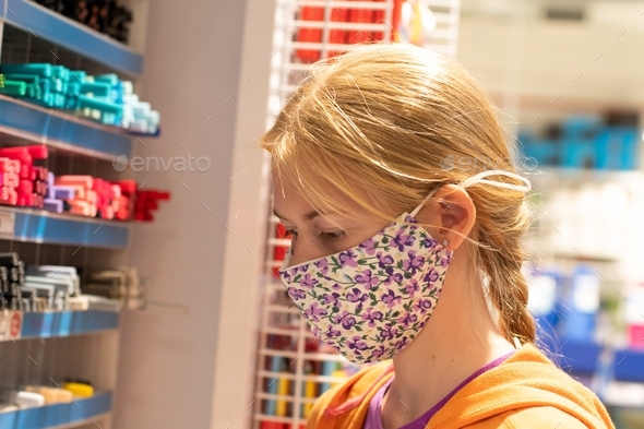 Teenage Girl wearing face mask in stationary shop store. New normal shopping. Back to school