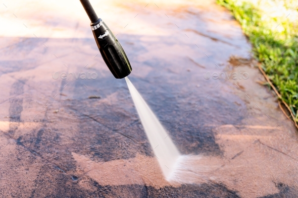 Washing dirty backyard tiles with high pressure cleaner. Spring clean up