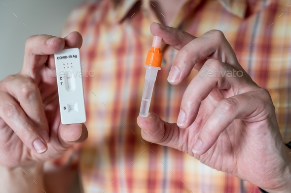 Man holding positive Covid-19 Antigen Rapid test kit and tube. Medical rapid diagnostic test