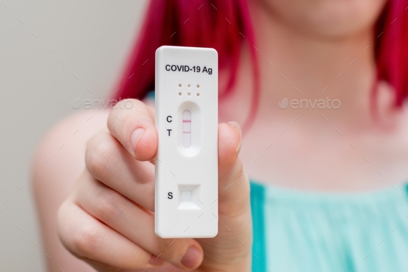 girl holding positive Covid-19 Rapid Antigen test result. rapid diagnostic test