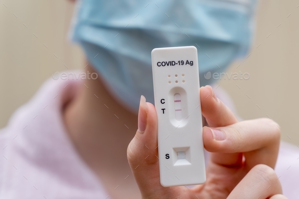 girl wearing face mask with positive Covid-19 Rapid Antigen test result. rapid diagnostic test