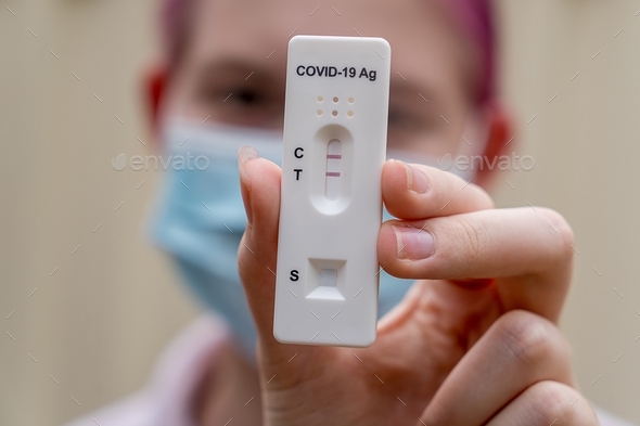 Gir wearing face mask with positive Covid-19 Rapid Antigen test result. rapid diagnostic test