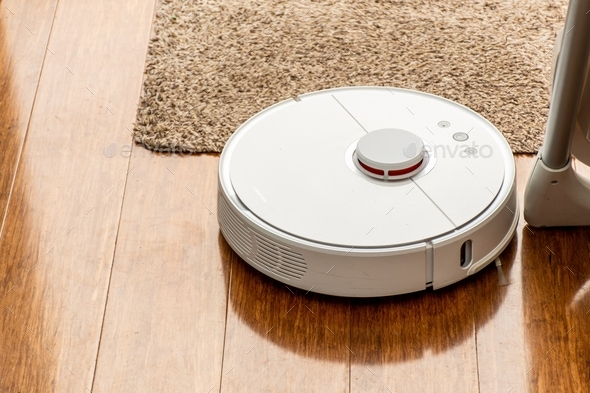 Robot vacuum cleaner cleaning vacuuming timber floor and rug. Cleaning at home