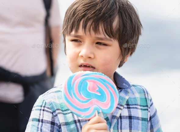 cute kid eating lollipop, Happy little boy holding big sugar candy,Child with smiling face eat sweet