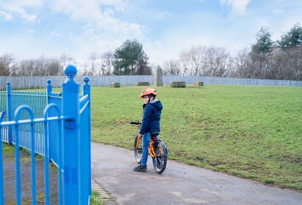 School kid learns to ride a bike in the Park, A lonely little boy on bicycle in grass fields
