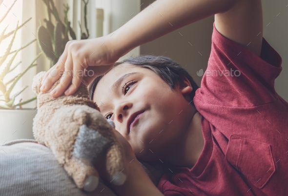 kid lying on sofa playing with dog toy,Smiling face Child boy playing with soft toy relaxing at home