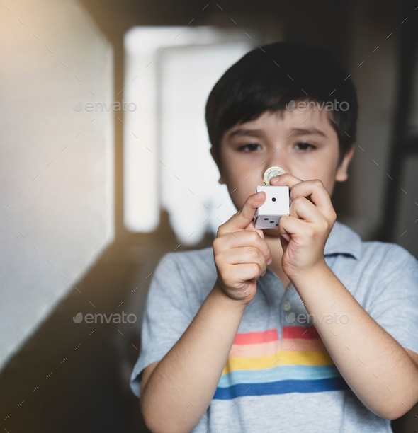 Blurry face of Kid holding one pound coin and white paper dice showing number one