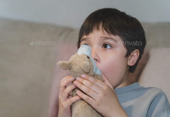 kid raising eyebrows and covering his mouth with dog toy being surprised and shock while watching TV
