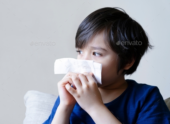 kid blowing nose into tissue, Child suffering from running nose, childhood wiping nose with tissue
